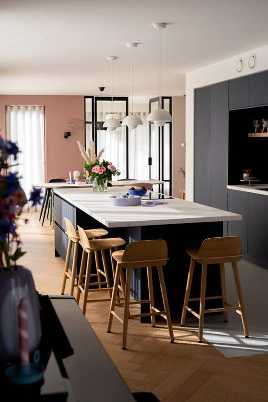 donkerblauwe keuken met houten barkrukken van muuto